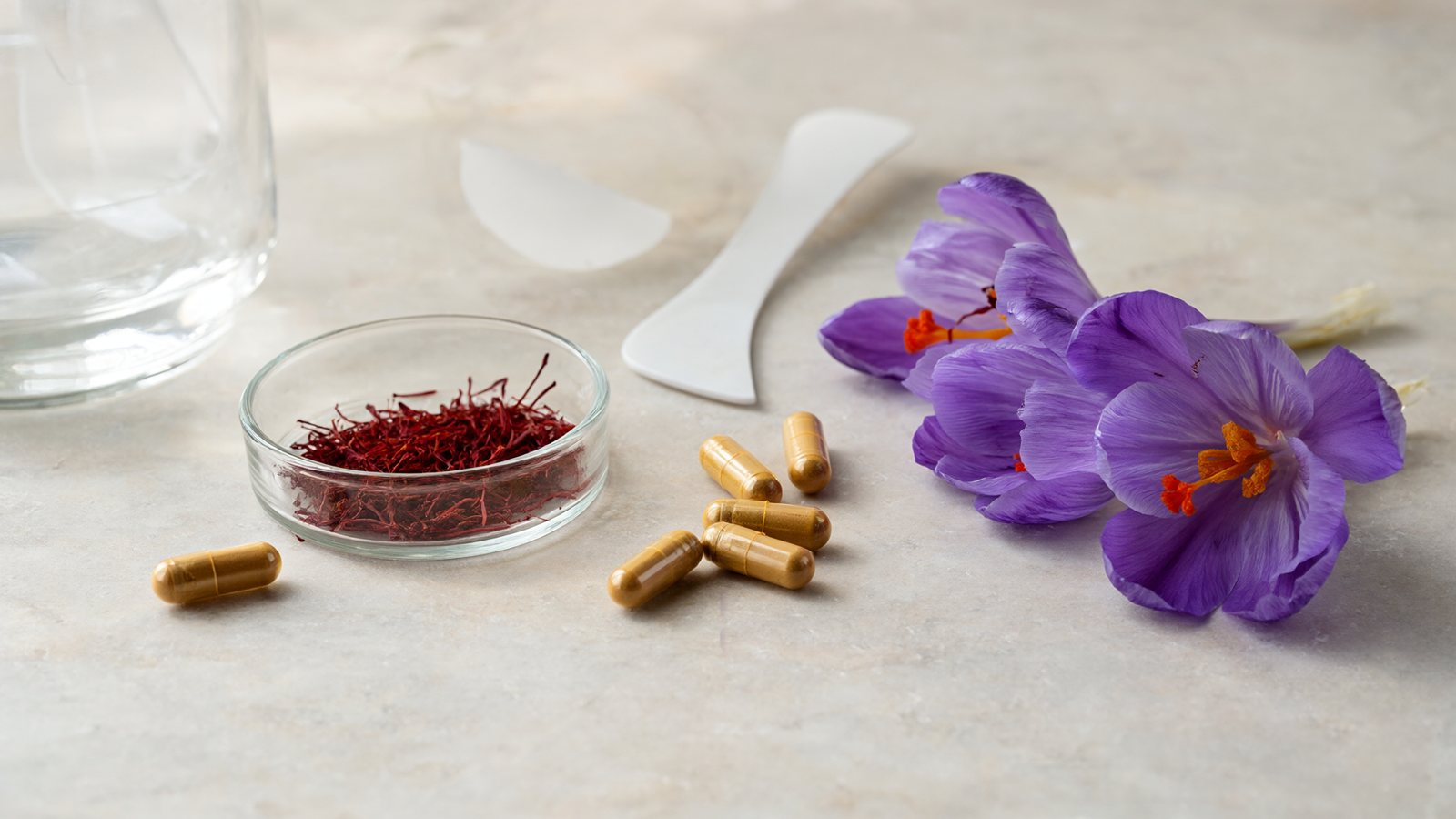 Affron saffron threads, crocus flowers and saffron extract capsules on a lab bench