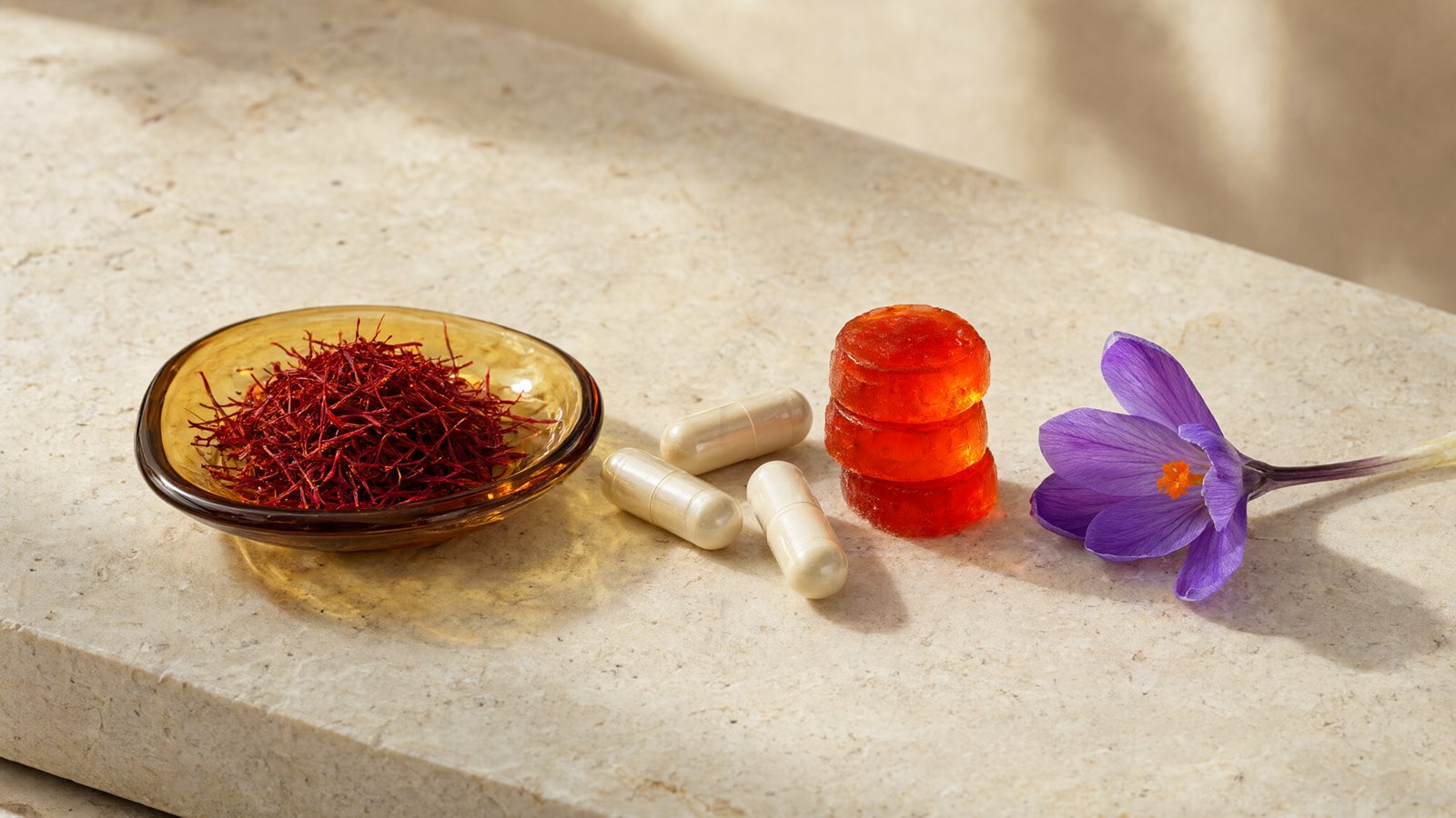 Saffron gummies vs capsules: saffron threads, vegetable capsules and orange gummies on stone