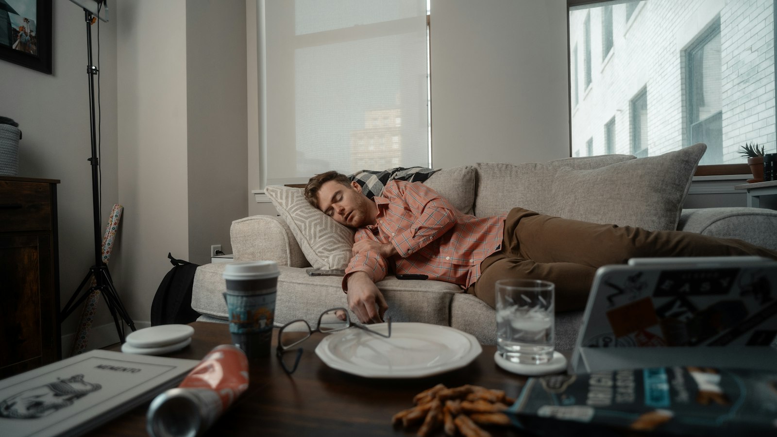 Tired after eating: a man asleep on a sofa beside an empty lunch plate and a glass of water