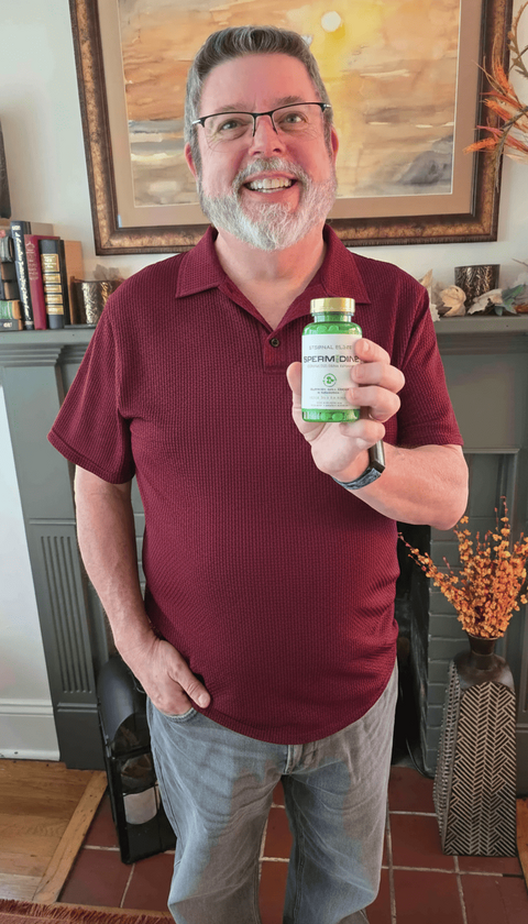 Person in a burgundy polo shirt holding an Eternal Elixir bottle indoors